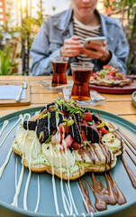 Delicious waffle dessert with fruits on the table of a street restaurant