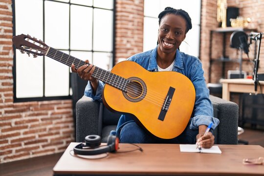 African american woman musician composing song playing classical guitar at music studio