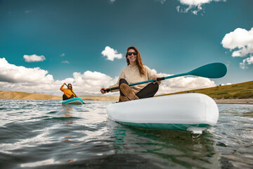 Two young girls walks on stand up paddle sup boards at calm mountain lake