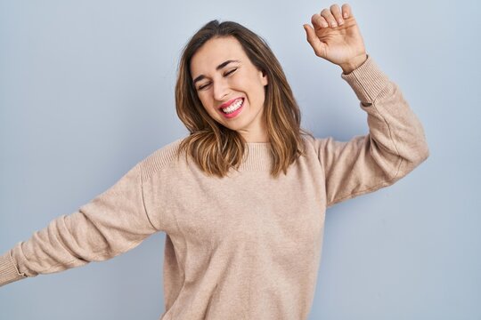 Young woman standing over isolated background dancing happy and cheerful, smiling moving casual and confident listening to music