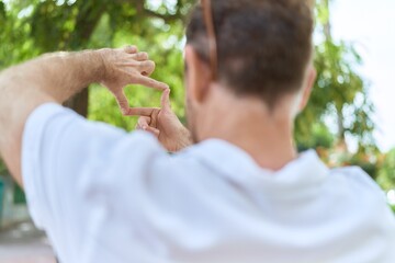 Middle age man doing photo gesture with hands at park