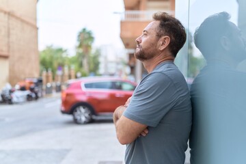 Fototapeta premium Middle age man looking to the side with serious expression and arms crossed gesture at street