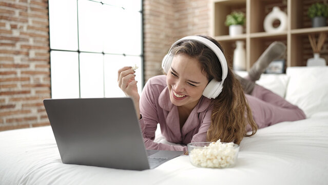 Young Beautiful Hispanic Woman Watching Movie Eating Popcorn At Bedroom