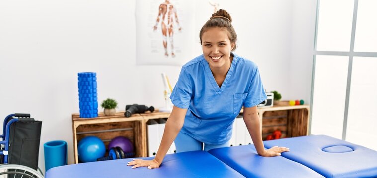 Young beautiful hispanic woman physiotherapist smiling confident standing at rehab clinic
