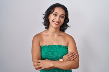 Young hispanic woman standing over isolated background happy face smiling with crossed arms looking at the camera. positive person.