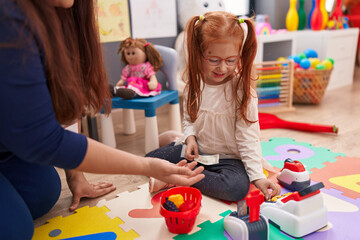 Adorable redhead girl playing money game sitting on floor at kindergarten