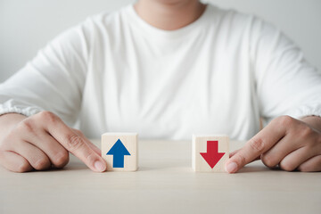 Woman with wooden block with up and down arrow concept of differentiation or Opposite direction.