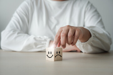 Concept of customer satisfaction review. Wooden blocks with facial emotion shows Happy and sad mood