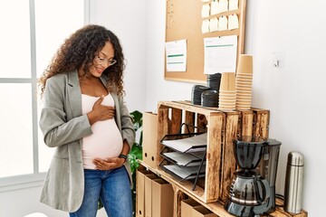 Young latin woman pregnant smiling confident standing at office