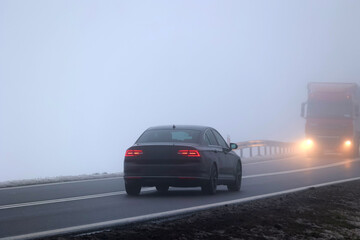 Samochody we mgle gęstej na drodze wieczorem. Niebezpiecznie.