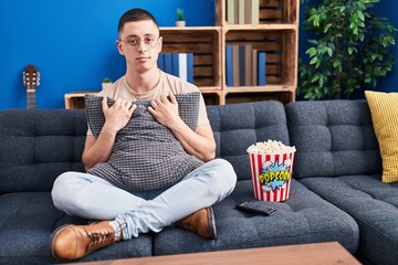 Young man eating popcorn relaxed with serious expression on face. simple and natural looking at the camera.