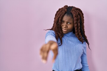 African woman standing over pink background pointing displeased and frustrated to the camera, angry...