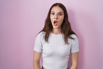 Fototapeta premium Young hispanic girl standing over pink background in shock face, looking skeptical and sarcastic, surprised with open mouth