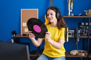 Young woman musician listening song holding vinyl disc at music studio