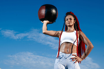 background sky. Athletic woman with med ball. Strength and motivation.Photo of sporty  woman in fashionable sportswear