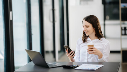 Confident Asian woman with a smile standing holding notepad and tablet at the modern office.