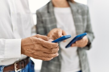 Middle age man and woman business workers using smartphone at office