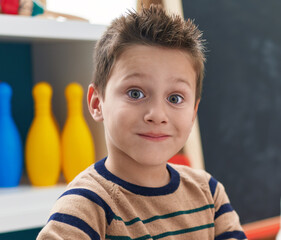 Adorable caucasian boy student smiling confident sitting on table at kindergarten