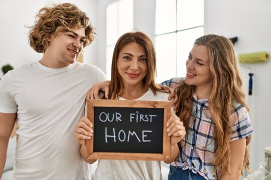 Mother and couple smiling confident holding our first house blackboard at home