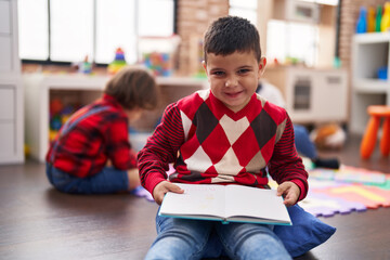 Two kids reading book sitting on floor at kindergarten © Krakenimages.com