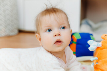 A six-month-old baby plays on the floor with colorful toys. The baby learns to crawl. portrait of a 6 month old baby