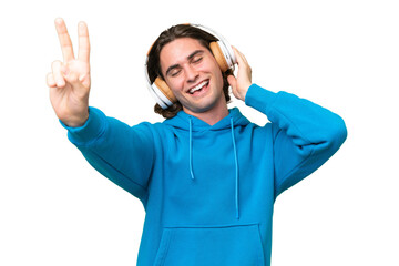 Young handsome man isolated on green chroma background listening music and singing