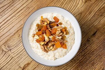 a delicious breakfast on a plate prepared in the restaurant. oatmeal with candied fruit and nuts
