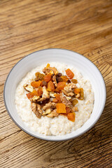a delicious breakfast on a plate prepared in the restaurant. oatmeal with candied fruit and nuts
