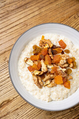a delicious breakfast on a plate prepared in the restaurant. oatmeal with candied fruit and nuts
