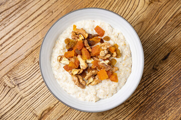 a delicious breakfast on a plate prepared in the restaurant. oatmeal with candied fruit and nuts
