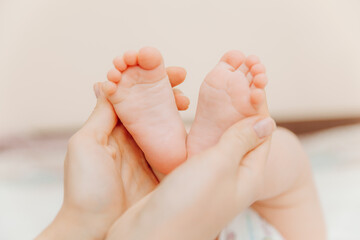 Obraz na płótnie Canvas Baby feet in mother's hands. Mom and her child. happy family concept. baby feet