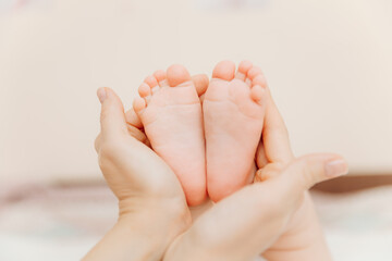 Obraz na płótnie Canvas Baby feet in mother's hands. Mom and her child. happy family concept. baby feet
