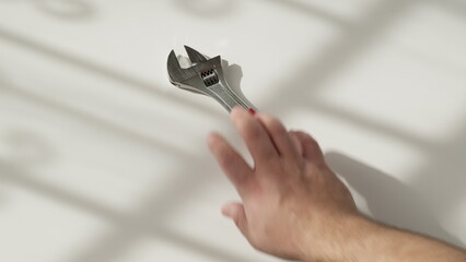 man hand take adjustable wrench from white background on floor. concept of worker and his tools....