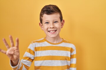 Young caucasian kid standing over yellow background showing and pointing up with fingers number four while smiling confident and happy.