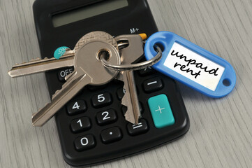 Trousseau de clés avec un porte-clés sur lequel est écrit loyer impayé en anglais posé sur une calculatrice
