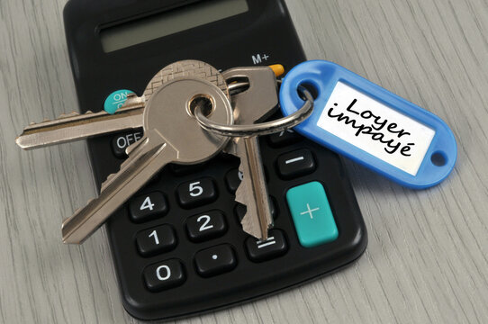  Trousseau de clés avec un porte-clés sur lequel est écrit loyer impayé posé sur une calculatrice