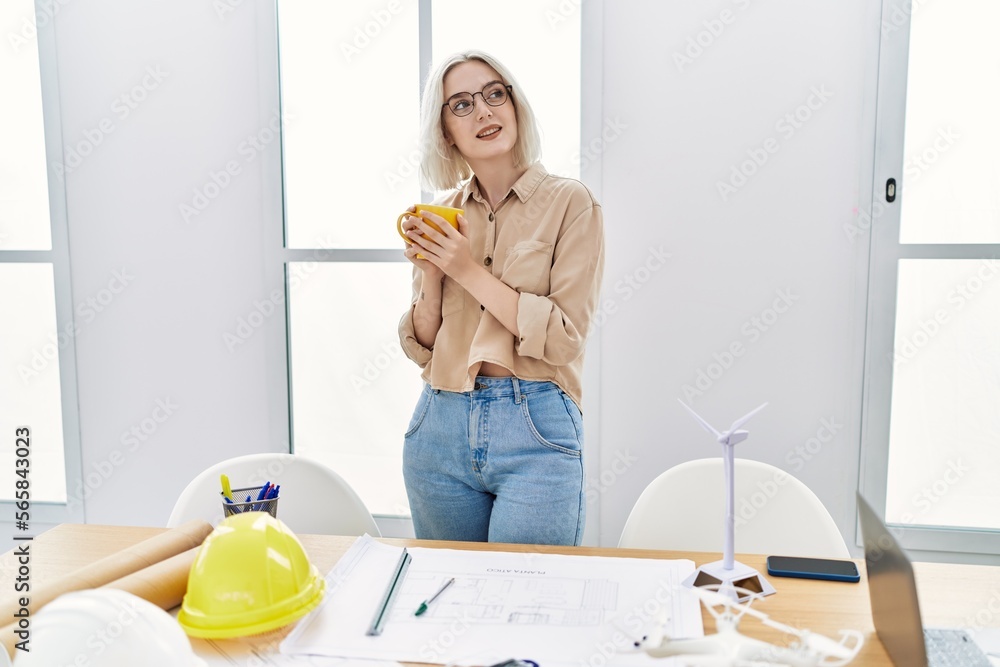 Poster young caucasian woman drinking coffee working at architect studio