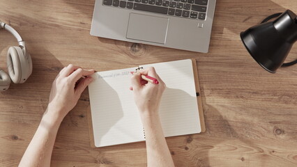 Top down view of woman hands writing in notebook title financial plan 2023. concept of business...