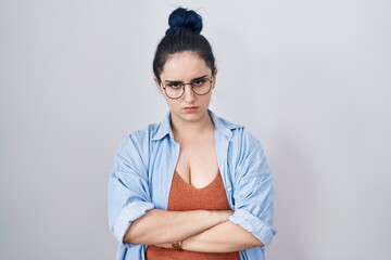 Young modern girl with blue hair standing over white background skeptic and nervous, disapproving...