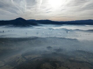 Aerial View. Flying over the high mountains in beautiful clouds. Aerial Drone camera shot. Air pollution clouds over Sarajevo in Bosnia and Herzegovina. 