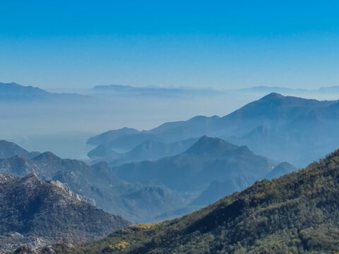 Panoramic view of dramatic karst mountain chains Dinaric Alps surrounding the Lake Skadar National Park seen from Goli Vrh, Montenegro, Balkan, Europe. Valley is covered by mystical fog, blue hills