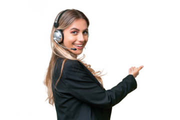 Telemarketer pretty Uruguayan woman working with a headset over isolated background pointing back