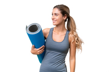 Pretty Young Uruguayan sport woman going to yoga classes while holding a mat over isolated background looking to the side and smiling