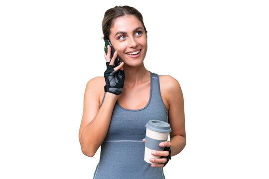 pretty Sport Uruguayan woman over isolated background holding coffee to take away and a mobile