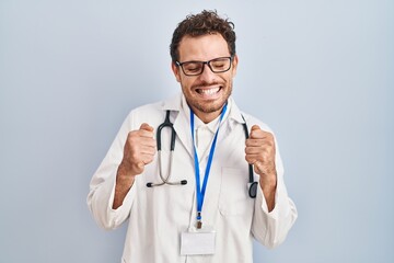 Fototapeta premium Young hispanic man wearing doctor uniform and stethoscope excited for success with arms raised and eyes closed celebrating victory smiling. winner concept.