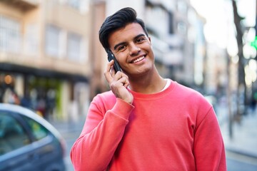 Young hispanic man smiling confident talking on the smartphone at street