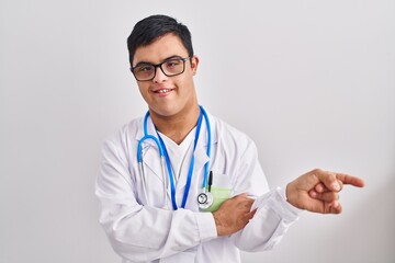 Fototapeta premium Young hispanic man with down syndrome wearing doctor uniform and stethoscope smiling happy pointing with hand and finger to the side