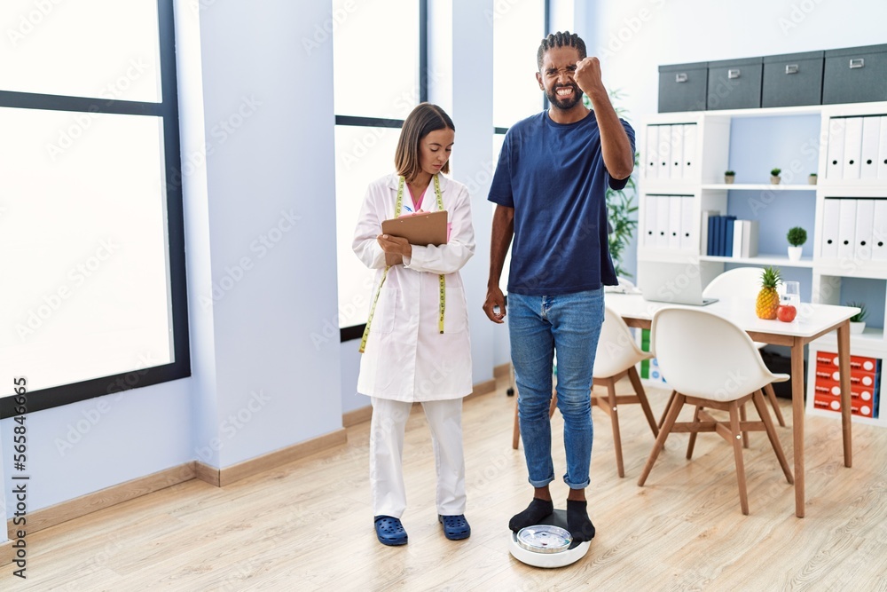 Poster dietitian at the clinic with client checking weight annoyed and frustrated shouting with anger, yell