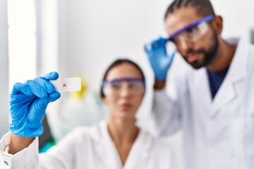 Man and woman scientist partners looking sample working at laboratory