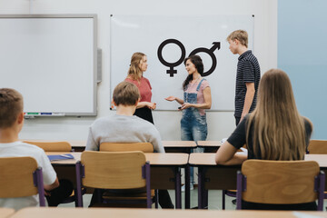 Young teacher is standing in front of the blackboard during sex education lesson - 565846809